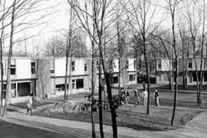 Black and white photo of Ridgewood Dorms, January 1951, with a few students visible amongst the trees in front of the buildings.