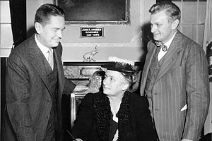 Signing for name change. Susan Brandeis Gilbert, daughter of Justice Brandeis, is seated with George Alpert on the right and another man on the left.