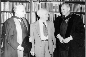 Israeli Prime Minister Ben-Gurion standing between Dr. Sachar on the left and George Alpert on right, during Ben Gurion's visit to Brandeis on  May 16, 1951. They are standing in front of a wall of bookcases.