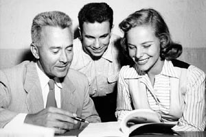 C. Ruggles Smith (Left) Registrar of Brandeis University 1946 to 1969, David Graubard (center) and Barbara Miller (right) look through a book. ca. 1957.
