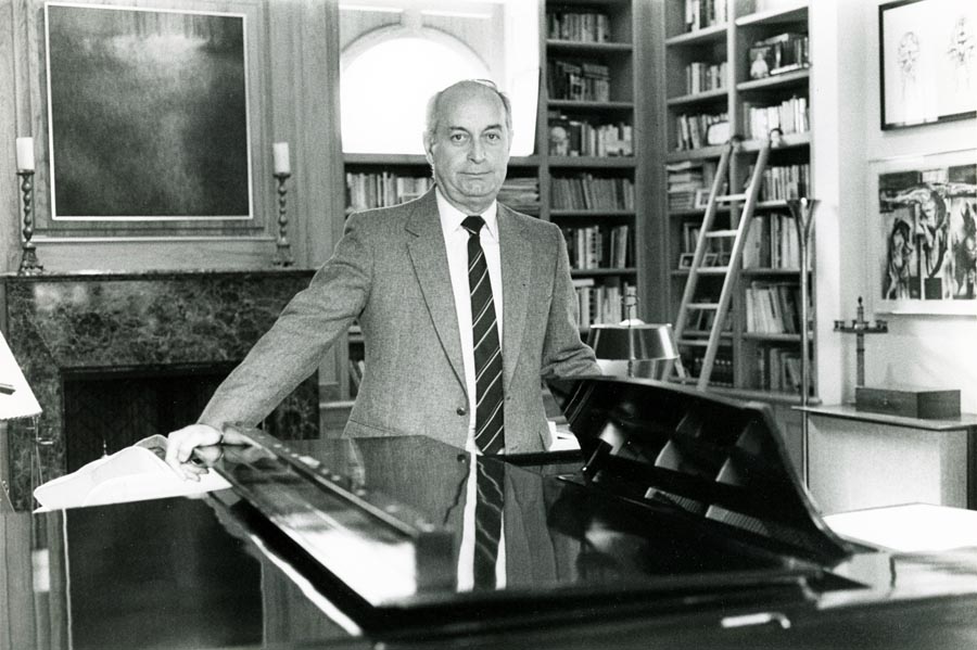 Man standing in front of piano with bookshelves in the background