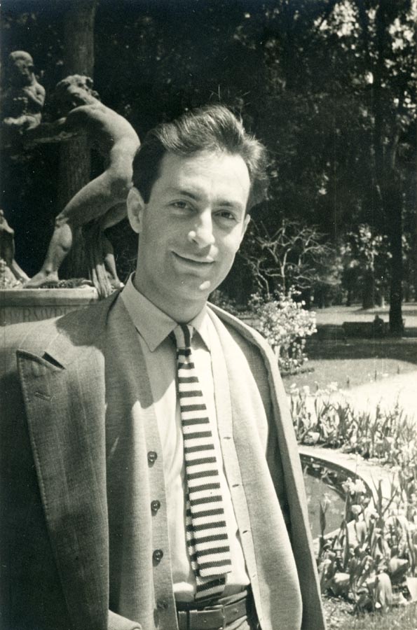 Young man standing by a sculpture fountain in a garden