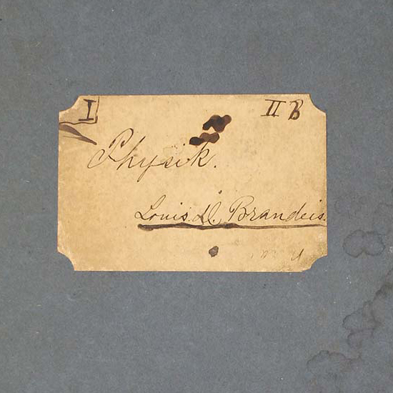 The stained cover of a blue notebook, which has a label with the German word 'Physik' and Louis D. Brandeis's signature (color photograph)