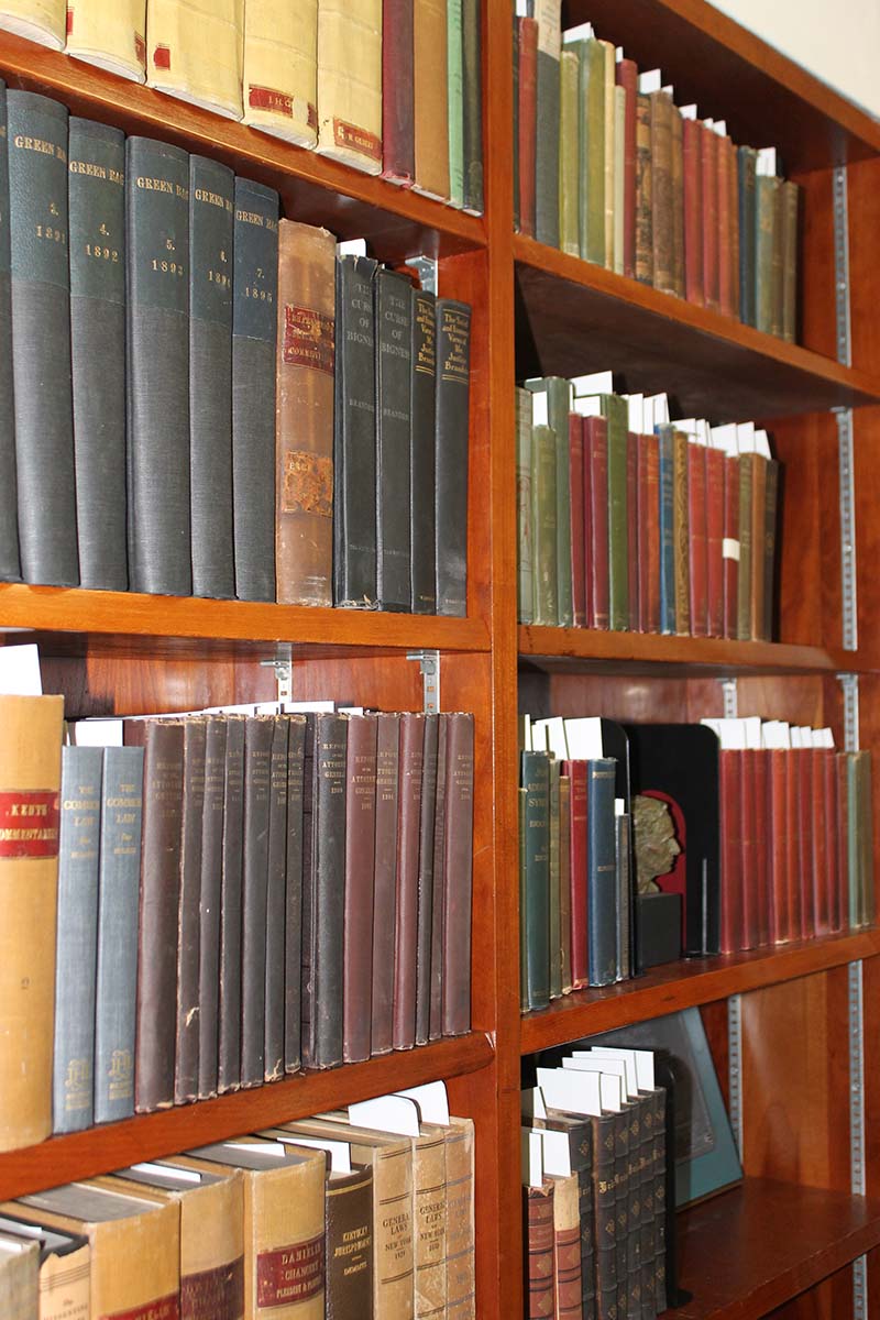 1) Bookcase with books and a small Brandeis bust, as seen in Louis D. Brandeis's Office Exhibit in the Brandeis University Library (color photograph)