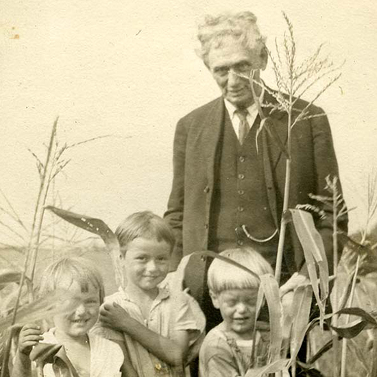 Louid D. Brandeis looking over his children as they stand in front of him looking at the camera iin the midst of a field