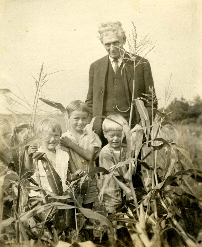 Louid D. Brandeis looking over his children as they stand in front of him looking at the camera in the midst of a field
