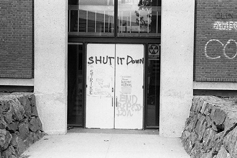 Graffiti on a campus building: "End Repression," "Shut It Down," "On Strike," "End the War! End Oppression."