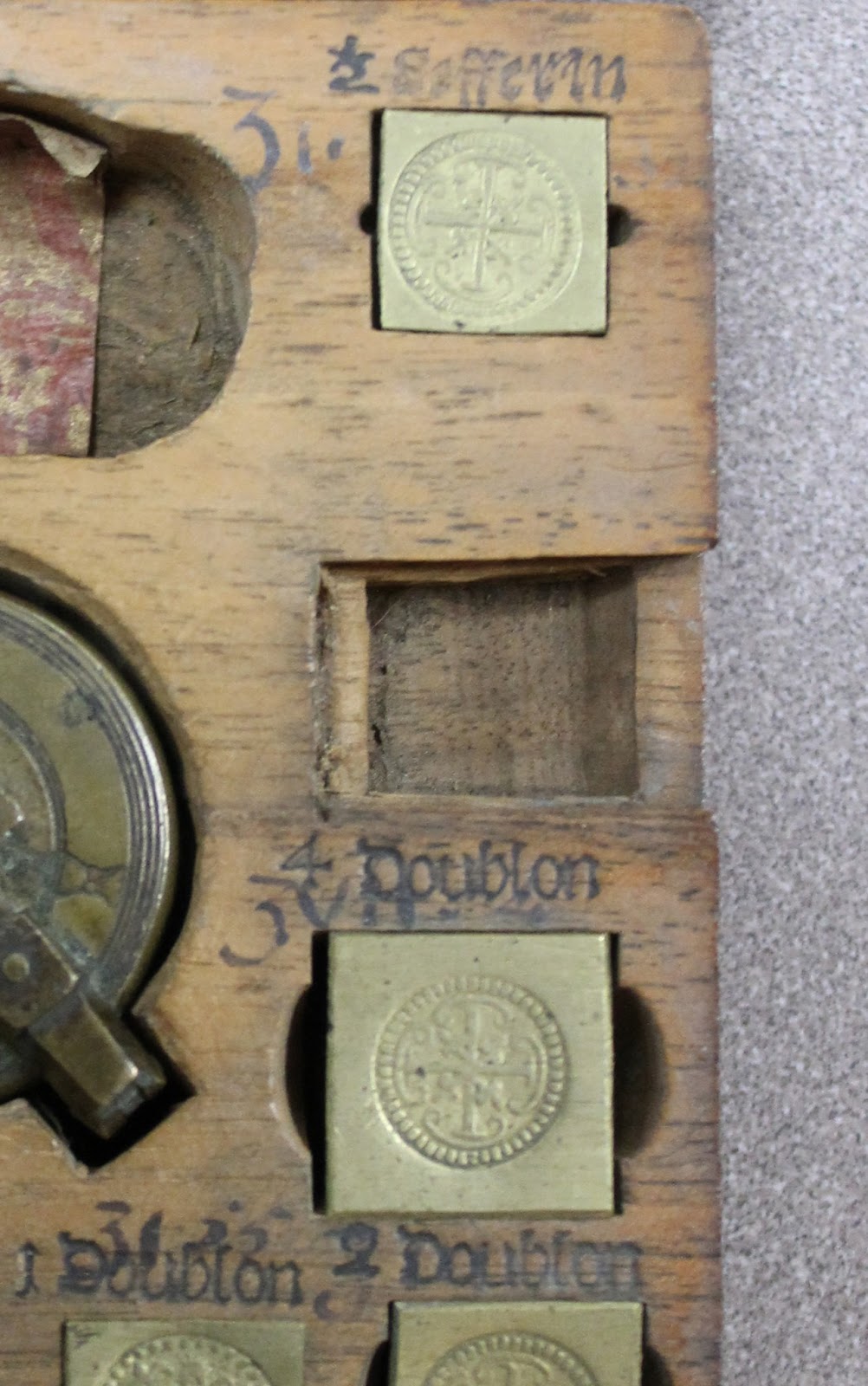 Grain weights set into built in compartments in the box. One compartment is empty.