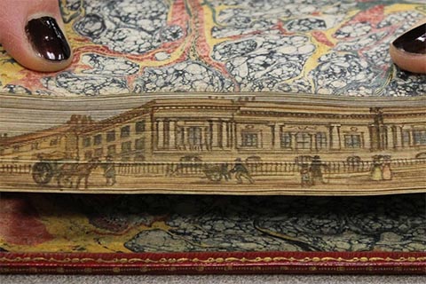 Colorful fore-edge painting of civilians and horses in front of a regal building that has columns
