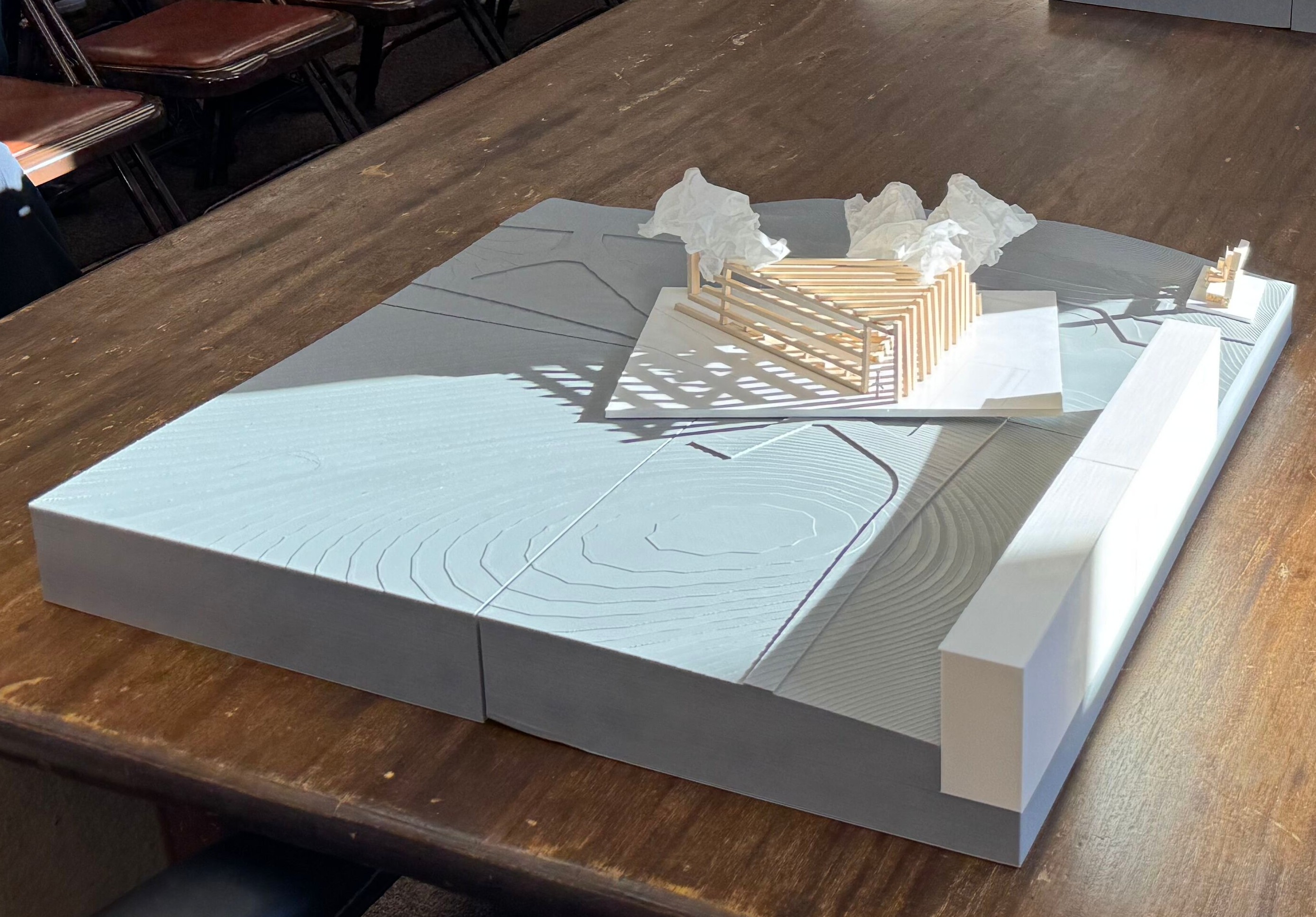 Architectural model of a landscape with a building, sitting on a desk. 