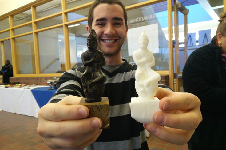 A student holds to small statues from CLARC