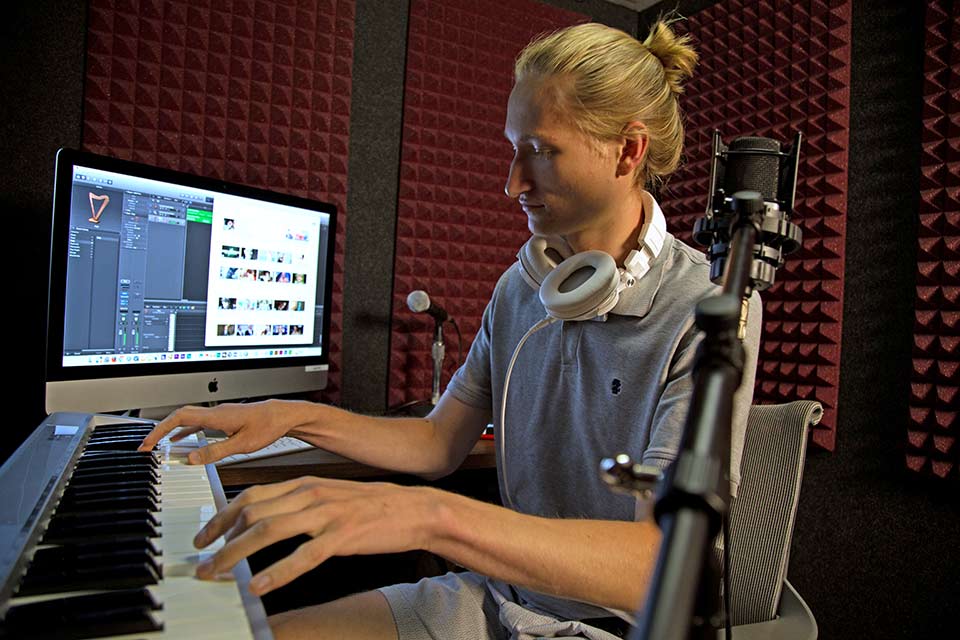 Person sitting at keyboard and computer in sound studio