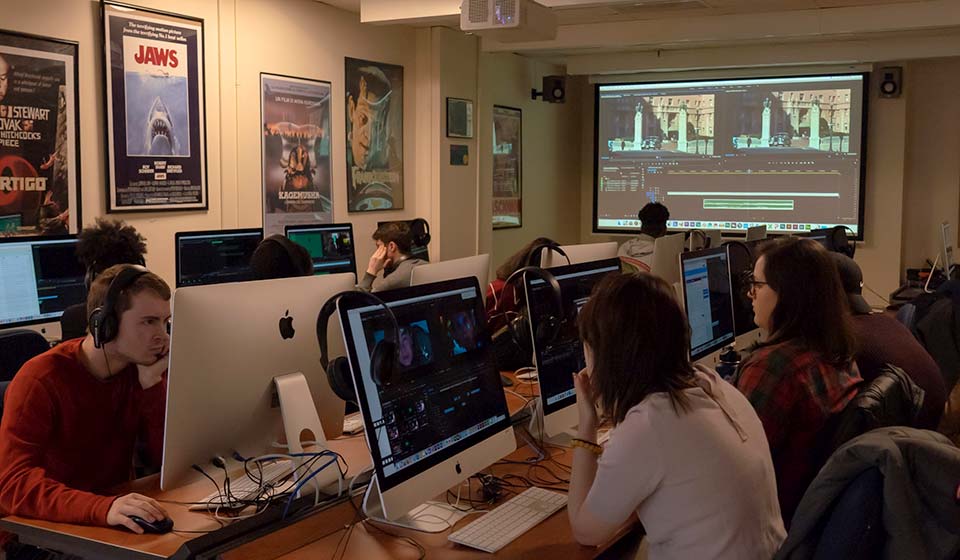 Students in a filmmaking class at work editing on the computers