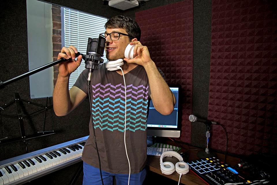 Person standing in the sound studio with headphones on holding a microphone
