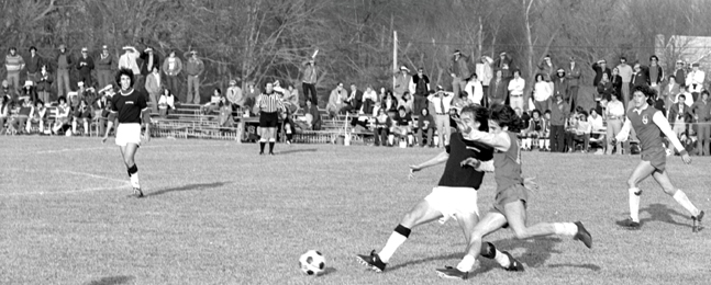 A Brockport State defender challenges  Michael Shannon ’78 at midfield.