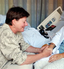 A hospital chaplain prays with a patient at the bedside.