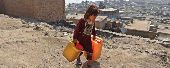 ALONG A HARSH PATH: A girl carries containers filled with water to her home in a hillside neighborhood in Kabul.