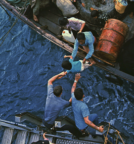 LIVES IN THE BALANCE: U.S. officials reach for a South Vietnamese child being transferred to a U.S. Navy ship.