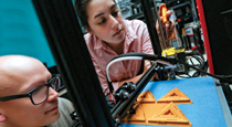 Ian Roy and Hazal Uzunkaya calibrate the extruder gear of a 3-D printer