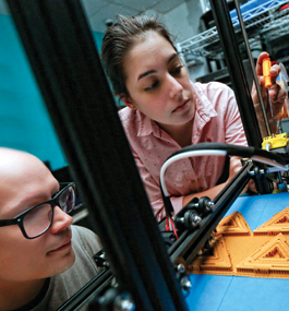 FABRICATING: Roy and Uzunkaya calibrate the extruder gear of a 3-D printer.