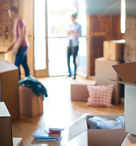 Photo of a young man and woman surrounded by moving boxes