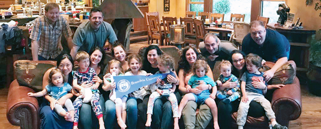 Alumnae and their families pose in a wood-paneled room.