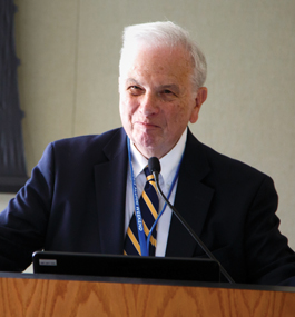 Photo of Sandy Lakoff standing behind a podium