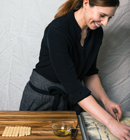 Photo of Meryl Feinstein rolling pasta dough on a wooden cutting board.