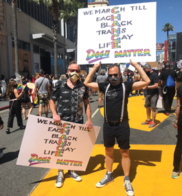 Photo of Steve Saklad and his husband holding signs that say "We march till each Black trans gay life does matter."