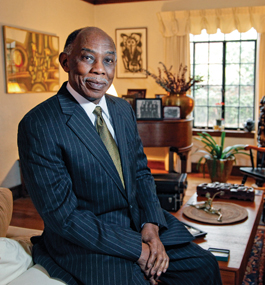 Photo of a smiling man dressed in a suit and tie sitting in a living room