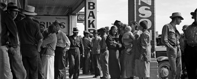 People of all ages wait in line outside a storefront.