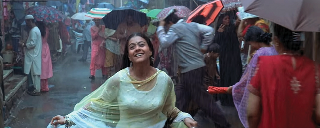 A woman in a pale green dress runs smiling through the rain with a crowd of people holding umbrellas in the background.