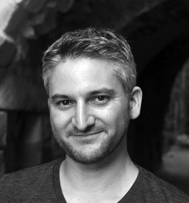 A black-and-white headshot of a smiling man with short graying hair.