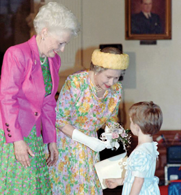 A photo of Lily Adams, when she was a small girl, just after she handed a little bouquet of flowers to Queen Elizabeth II of Great Britain. Ann Richards stands to the right of the queen and beams down at Lily.
