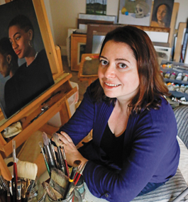 Photo of Elana Hagler, sitting in front of a painter's easel