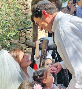 Photo of groom bending down to look at woman in white veil