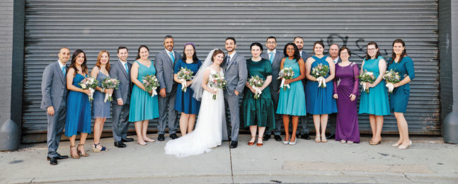 Photo of a bride and groom flanked on either side by long line of men and women