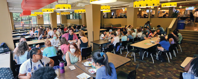 Students eat and talk at dining-hall tables.