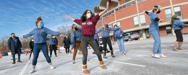 Students dance in a campus parking lot.