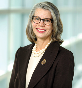 Head shot of a smiling woman wearing dark-framed glasses