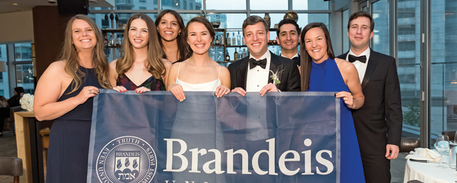 Bride and groom holding a large Brandeis banner with six people in formal dress