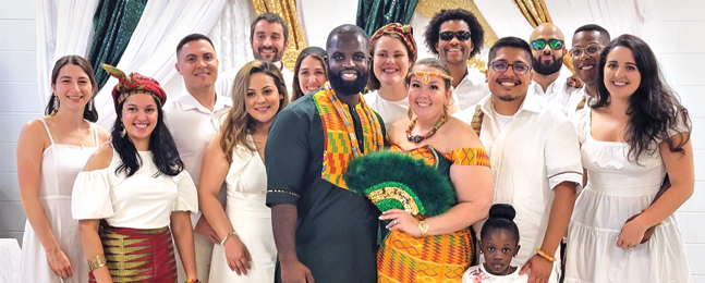 Bride and groom wearing traditional African prints surrounded by friends and family dressed in white clothes