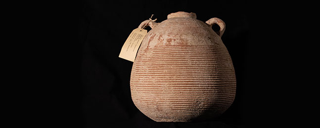 Photo of a brown jar, round in shape,  with two small handles on either side near the small mouth.
