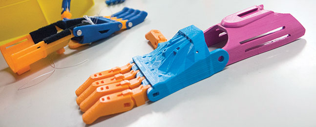 Photo of two devices, made of orange and blue plastic, that are hinged like hands.