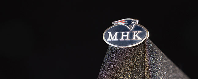 A photo of a pin emblazoned with the New England Patriots logo and the initials "MHK."