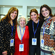 Four women from different generations smile at the camera