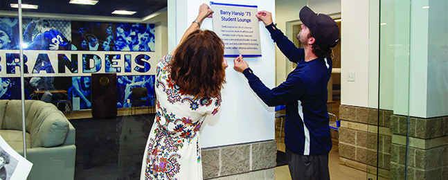 A woman and man install a naming plaque outside a room