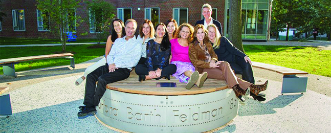 A group of people sit on a round plinth in a quad