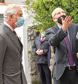 Photo of Michael Mail gesturing upward with King Charles III by his side.