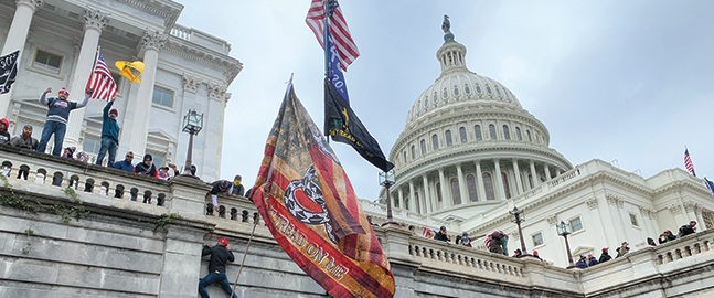 Photo of people with insurrection flags standing atop an outside wall of the U.S. Capitol on Jan. 6, 2021.